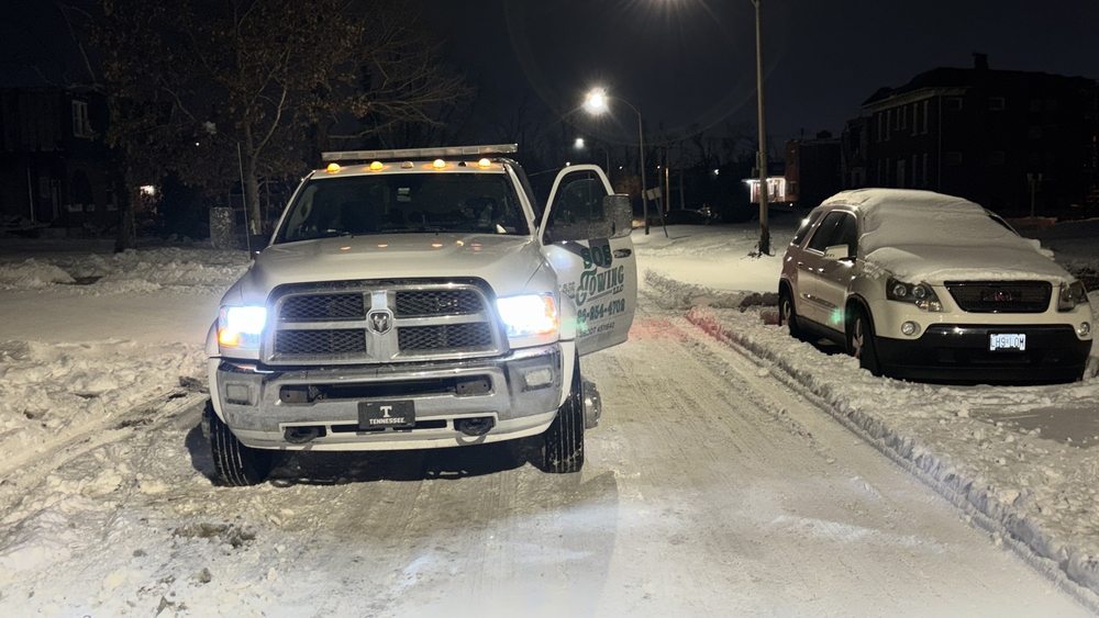 SOS Towing truck with amber lights working a snow-covered street at night