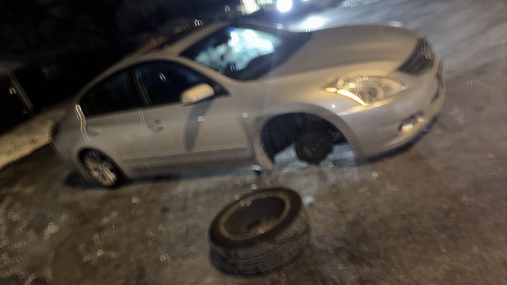 Sedan with a removed wheel during a night-time tire change